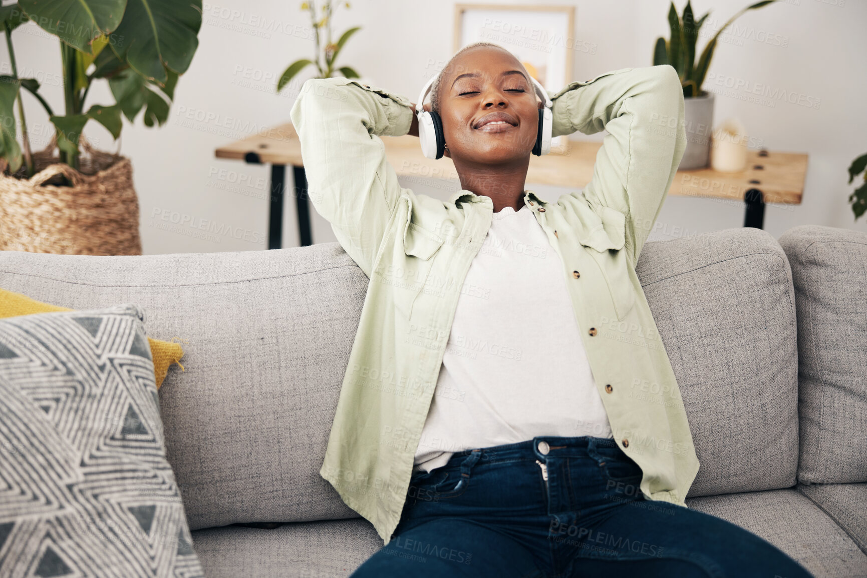 Buy stock photo Black woman, relax and listening to music on sofa in home, living room and lounge with peace, headphones and rest on weekend. Happy, face and streaming audio with zen, freedom and tech in apartment