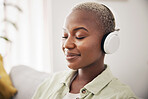 Black woman, listening and meditation podcast on headphones in home, living room or peace on sofa in lounge. Music, tech and happiness on face of person with zen, mindset and wellness in apartment