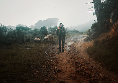 Buy stock photo Back, winter hiking and a man in nature for freedom, travel or adventure in the mountain wilderness. Forest, morning and overcast with a male backpacker on a dirt road in the woods for a hike