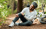 Man, knee pain and injury in forest with bike, stress and sitting on ground with emergency in nature. Cycling athlete, young guy and accident with bicycle, training and exercise with crash in woods