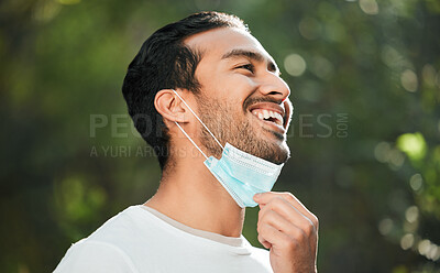 Buy stock photo Smile, mask and remove with a man breathing fresh air in nature, feeling happy at the end of restrictions. Covid, freedom and post lockdown with a young person in the forest, woods or wilderness