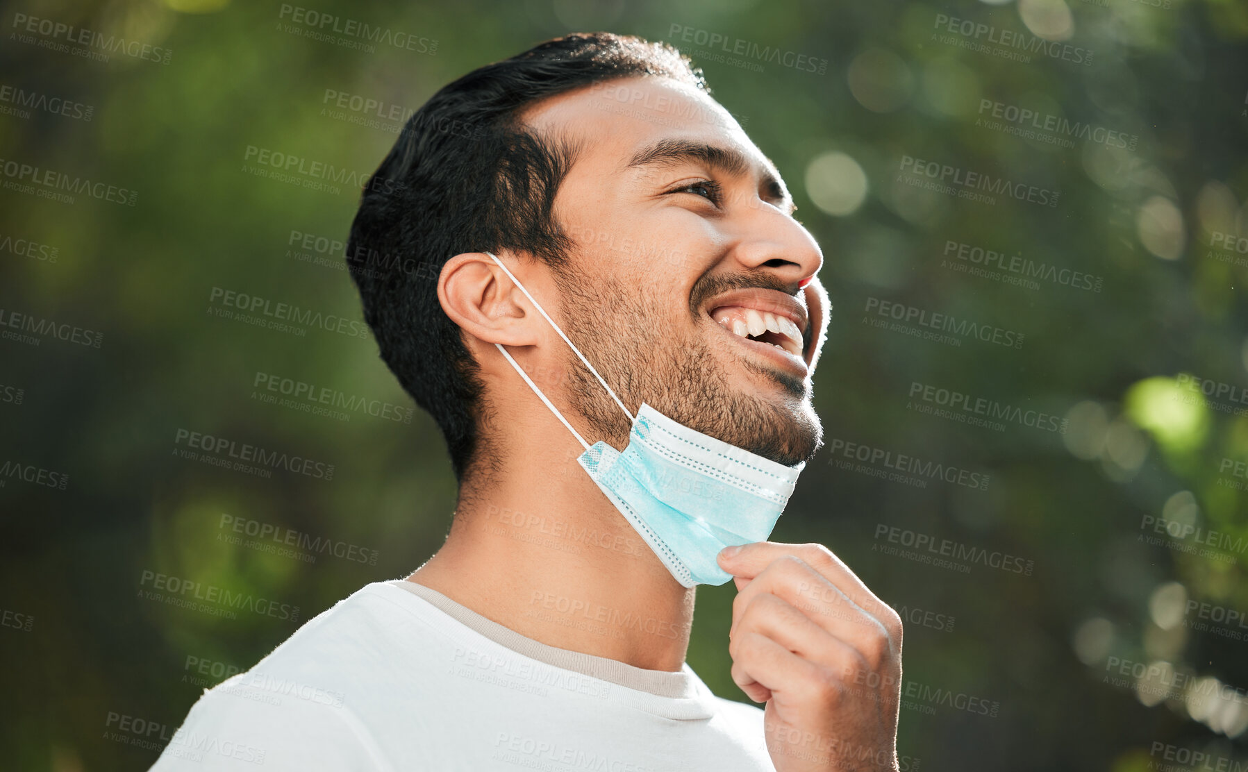 Buy stock photo Smile, mask and remove with a man breathing fresh air in nature, feeling happy at the end of restrictions. Covid, freedom and post lockdown with a young person in the forest, woods or wilderness