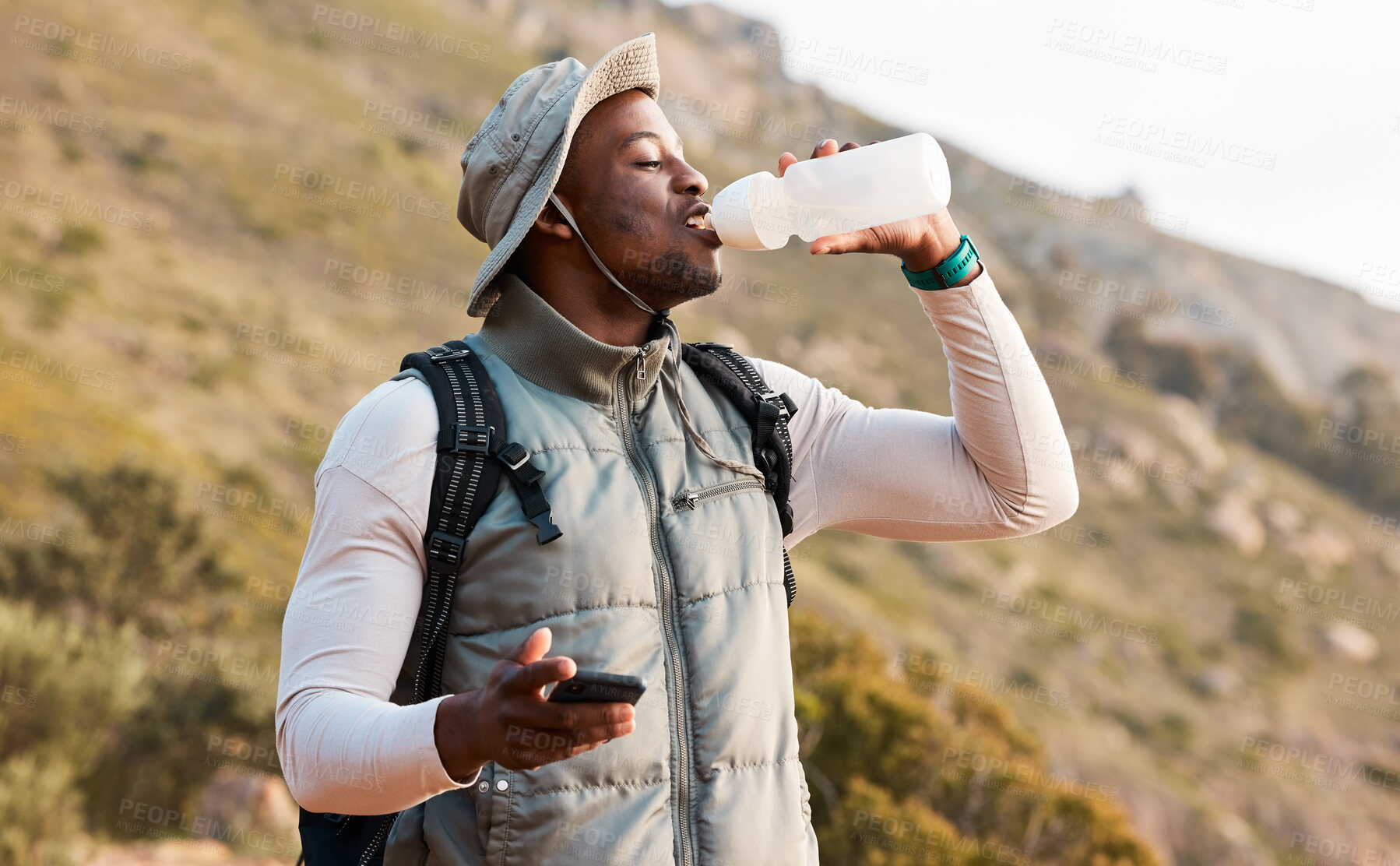 Buy stock photo Hiking, water bottle and black man with a smartphone, connection and hydration with fitness. African person, guy or hiker with a cellphone, mountain or thirsty with health, network or drinking liquid