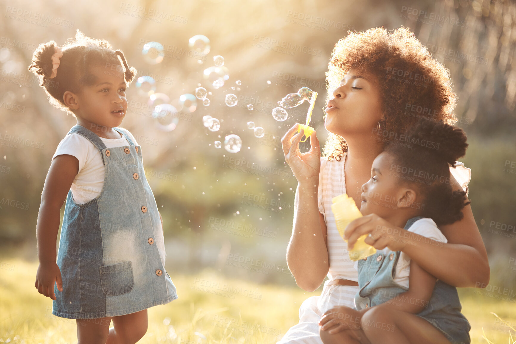 Buy stock photo Nature, children and mother blowing bubbles in an outdoor park for playing, bonding or having fun. Happy, love and young mom sitting with her girl kids in a field or green garden in summer in Mexico.