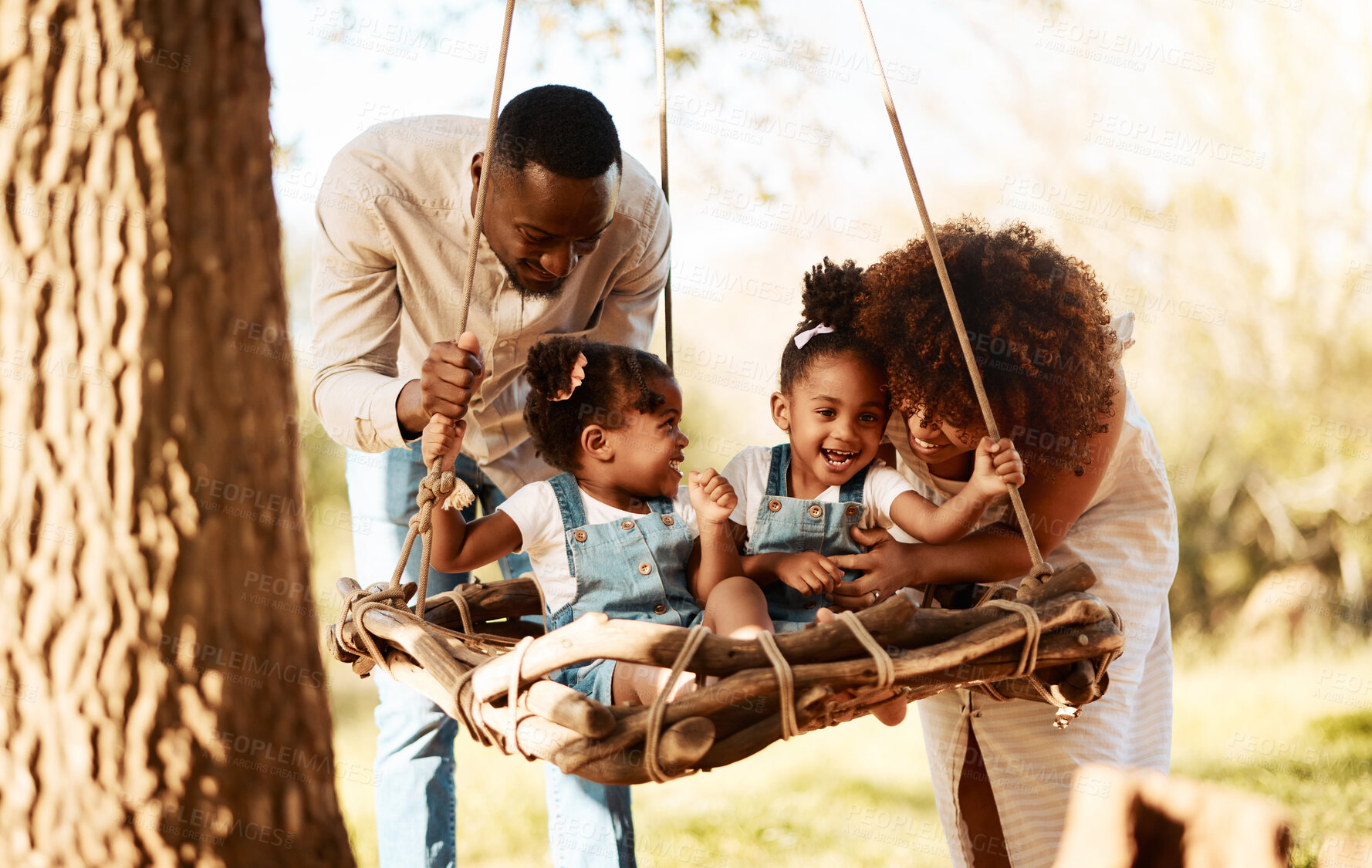 Buy stock photo Parents with kids in park, tree swing and freedom for love, bonding or peace in nature together. Mother, father and children adventure in garden, black family on summer weekend in woods or forrest.