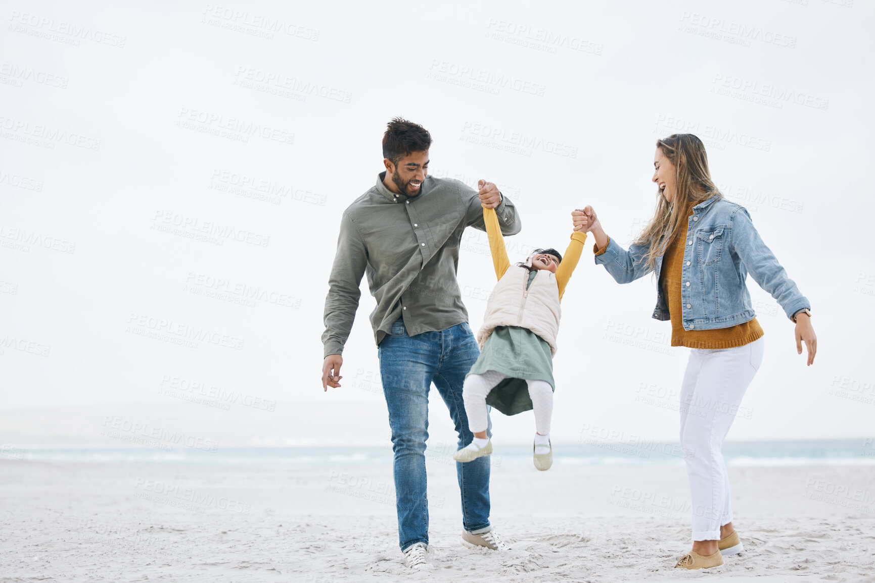 Buy stock photo Swinging, holding hands and a family at the beach for walking, bonding or playing together. Happy, playful and a mother, father and boy kid at the ocean for a holiday, relax and love during travel