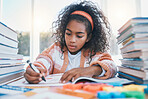 Education, creative and child coloring in a book for artistic project, assignment or assessment. Crayon, hobby and girl kid student writing for learning in a notebook for homework by a desk at home.