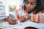 Education, homework and child coloring in a book for artistic project, assignment or fun. Colors, hobby and girl kid student writing for creative learning in a notebook by a desk at modern home.