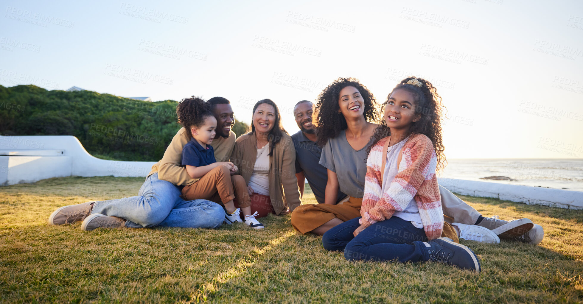 Buy stock photo Beach, smile and family relax on vacation, bonding and having fun together on grass on mockup space. Grandparents, happy and interracial parents with kids at ocean to travel on holiday, care and love