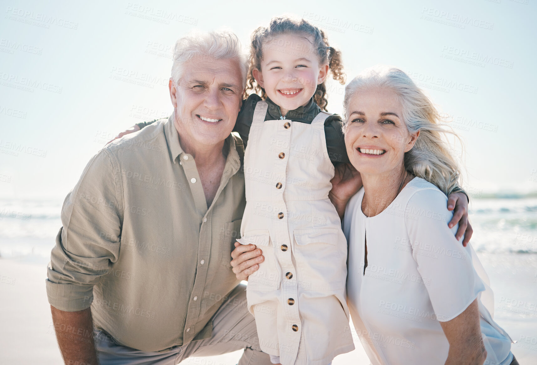 Buy stock photo Smile, portrait and grandparents with child on beach for travel, summer vacation and relax. Love, support and care with family hugging on seaside holiday for bonding, happiness and break together