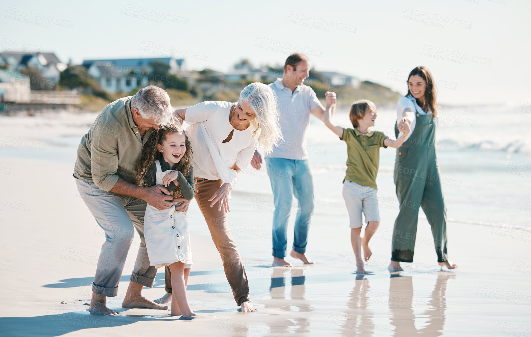 Buy stock photo Grandparents, children and big family with play at beach, comic laugh or bonding for love, sunshine or excited on vacation. Mom, dad and kids by sea, waves and freedom on holiday for summer in Spain