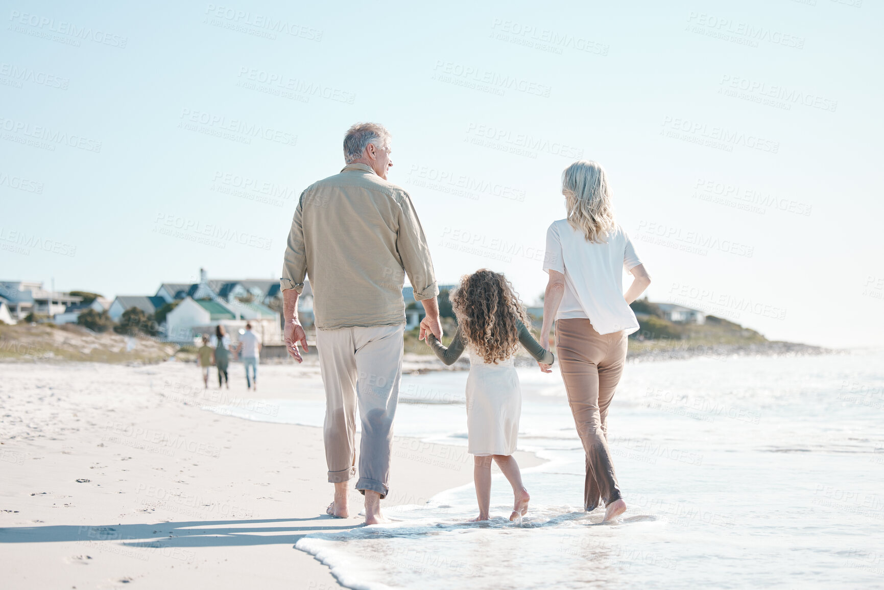 Buy stock photo Relax, holding hands and grandparents with child at beach for travel, love and support. Summer vacation, care and retirement with family walking on seaside holiday for adventure, bonding and peace