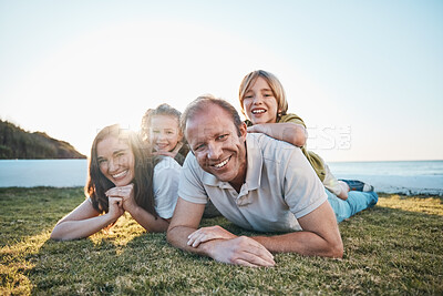 Buy stock photo Family, parents and portrait of children on grass by ocean for bonding, relationship and relax together. Nature, sunlight and happy mother, father and kids on holiday, vacation and travel by sea