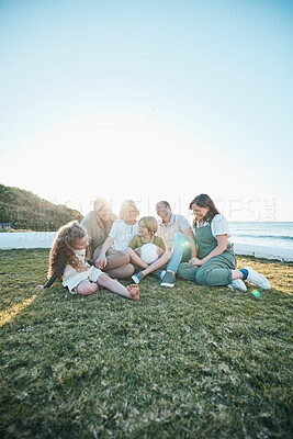 Buy stock photo Family, grandparents and kids on grass by ocean for bonding, relationship and relax together. Nature, parents and happy grandmother, grandfather and children on holiday, vacation and travel by sea