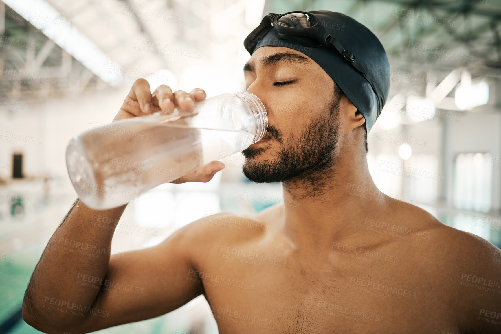 Buy stock photo Man, swimmer and drinking water for hydration, exercise or training workout at indoor swimming pool. Active and thirsty male person or athlete with mineral drink for sustainability, fitness or cardio