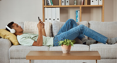 Buy stock photo Man, relax on couch with headphones and smartphone, scroll social media and music with communication at home. Online, audio streaming and connectivity with internet, radio or watch video with chat