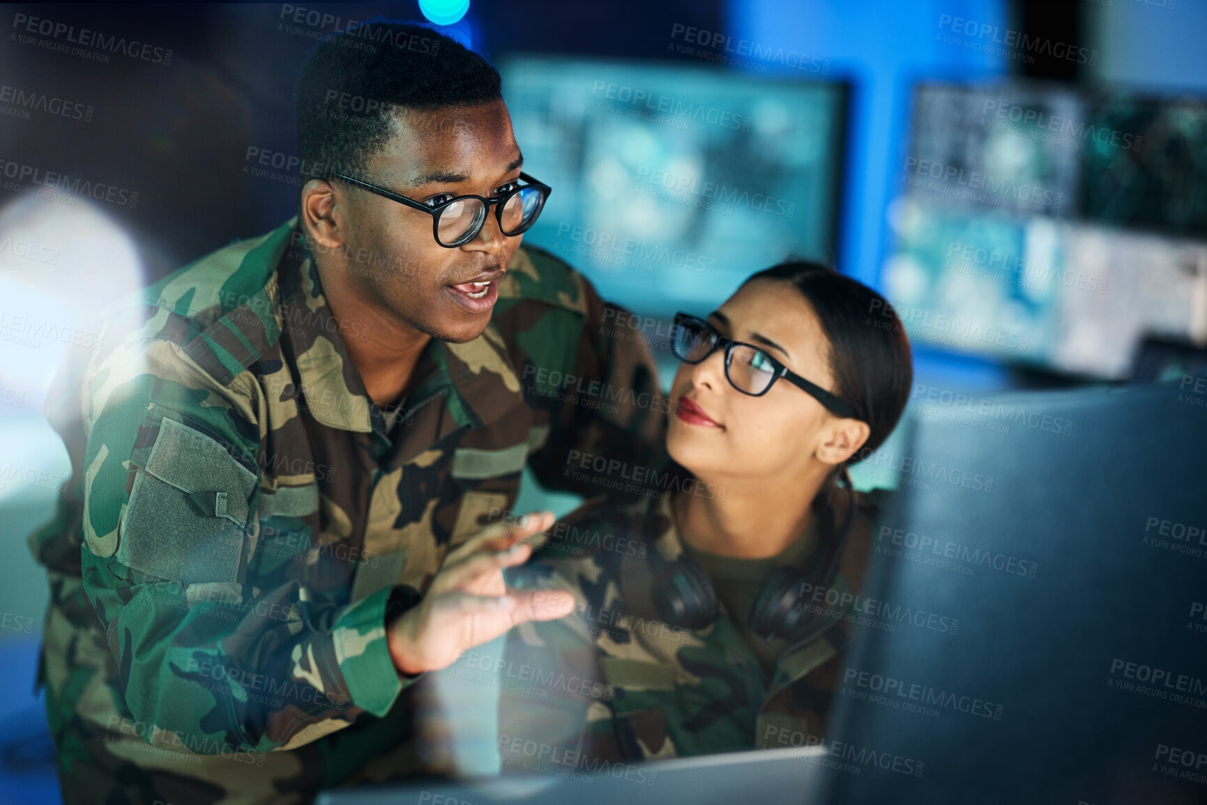 Buy stock photo Night training, army and people with a computer for communication, planning strategy or surveillance. Cyber security, data center and a black man talking to a woman about monitor in a military room