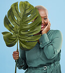 Black woman, monstera leaf and beauty in portrait, natural cosmetics and fashion on blue background. Silk green dress, eco friendly skincare and dermatology, African model glow and plant in studio 