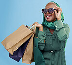 Shopping, sunglasses and black woman with bags, retail and luxury items on a blue studio background. African person, customer and model with expensive clothes, client and boutique products with sales