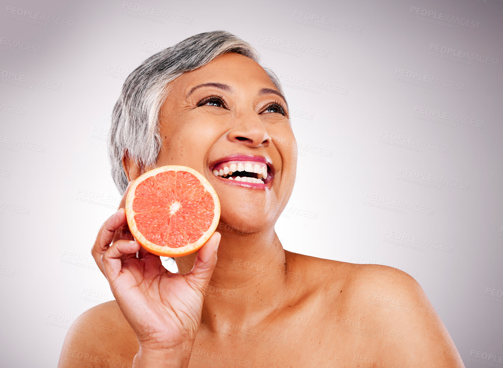 Buy stock photo Senior, happy woman and grapefruit for vitamin C, skincare or natural nutrition against a studio background. Mature female person smile with organic citrus fruit for collagen, detox or diet on mockup