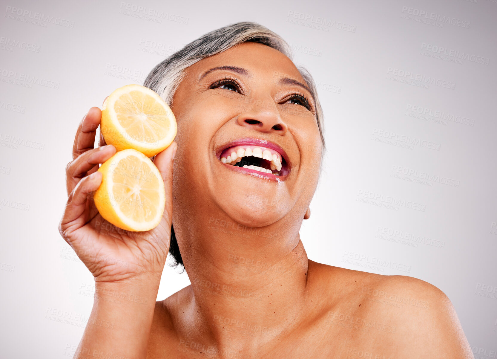 Buy stock photo Senior, happy woman and lemon for vitamin C, skincare or natural nutrition against a studio background. Mature female person smile with organic citrus fruit for collagen, detox or diet on mockup