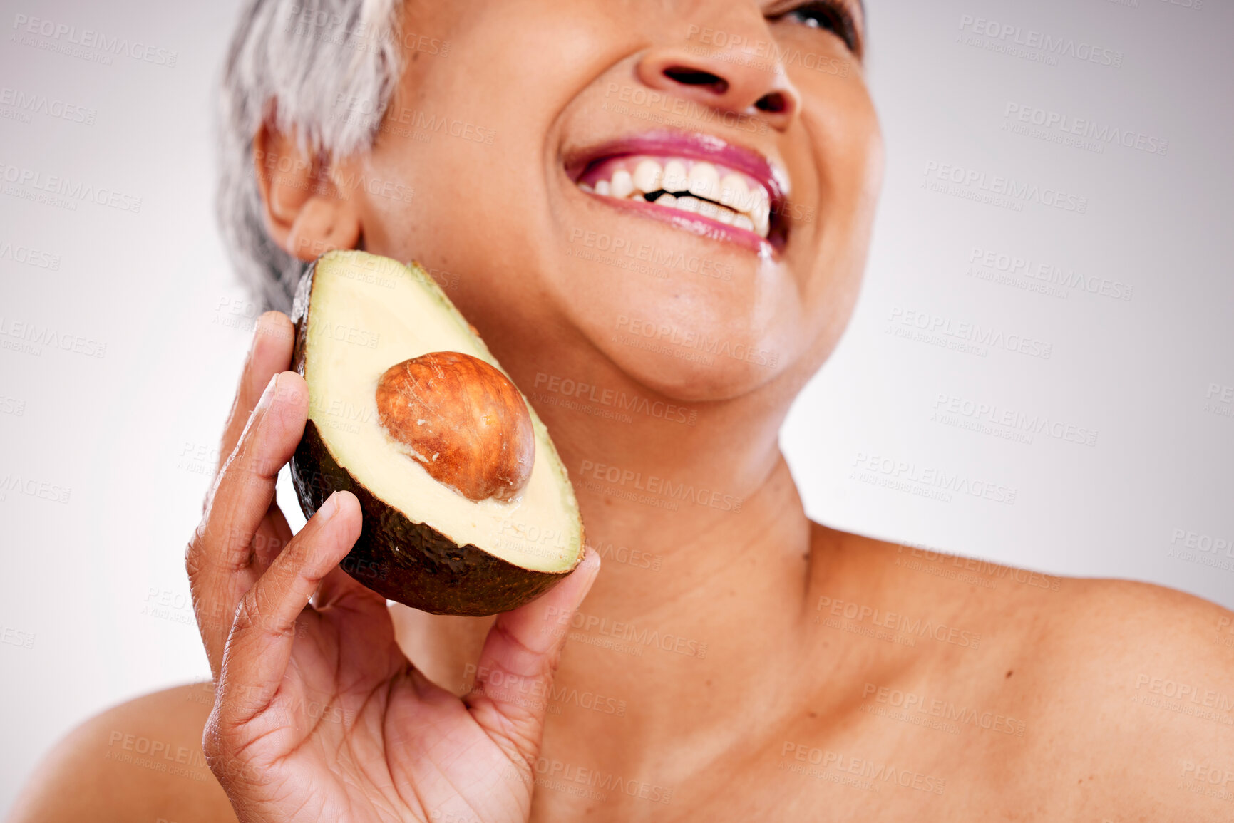 Buy stock photo Senior, happy woman and avocado in skincare or natural nutrition against a studio background. Closeup of mature female person or vegan smile with fruit or vegetable in detox, diet or healthy wellness