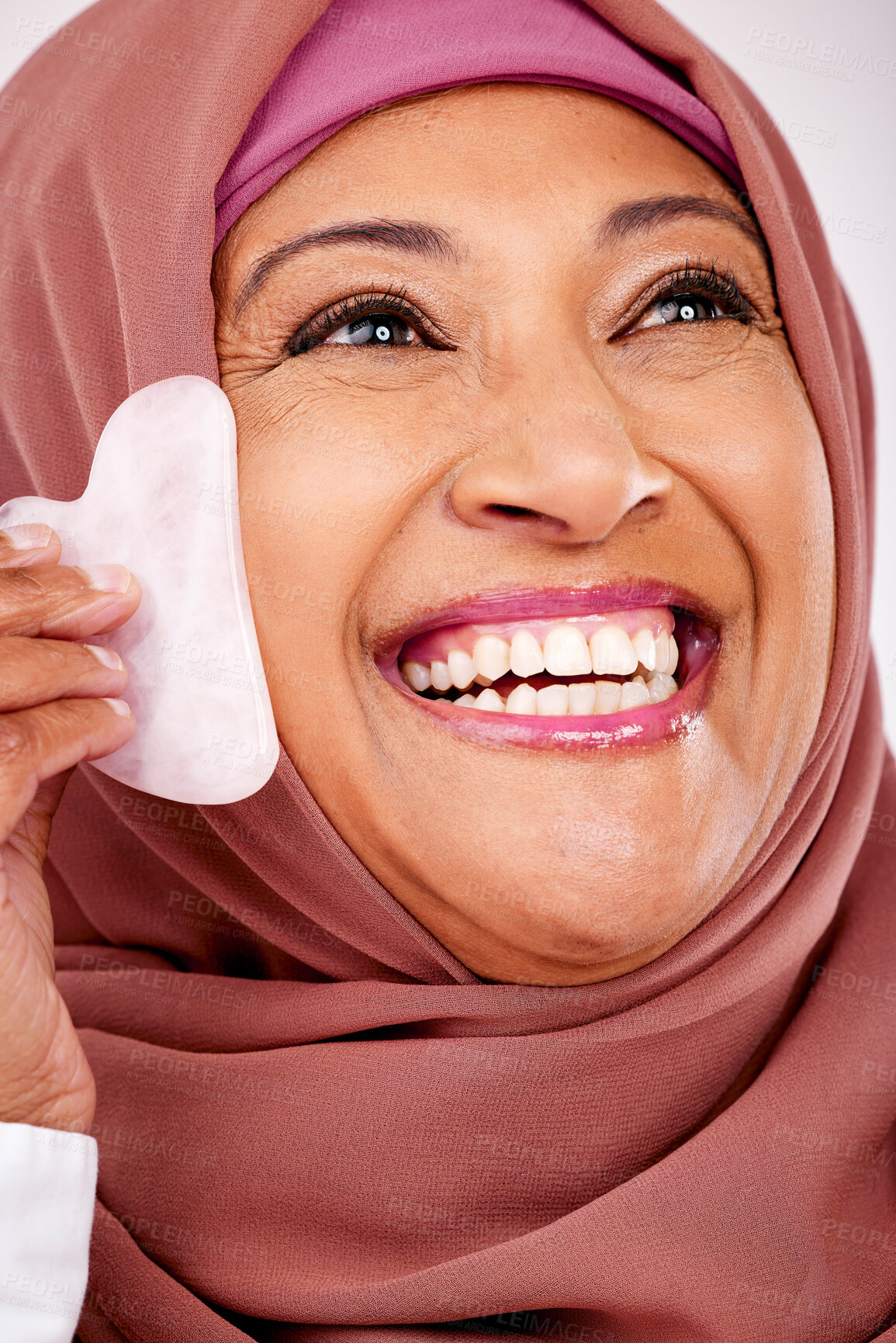 Buy stock photo Skincare, gua sha stone and face of muslim woman closeup in studio on a white background for beauty. Spa, smile and natural with a happy mature arab person, massage with stone for antiaging treatment