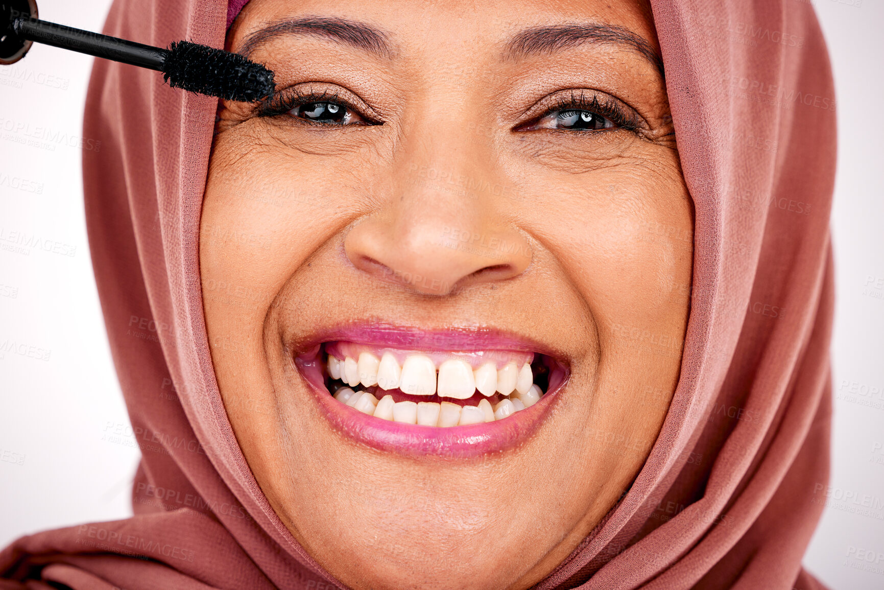 Buy stock photo Portrait, Muslim woman and smile with makeup, mascara and cosmetics on a white studio background. Face, Islamic person and model with a hijab, dermatology and facial with a product, glow and shine