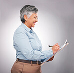 Studio, clipboard and mature happy woman writing checklist, inspection information or survey feedback. Happiness, paperwork and business manager working on project schedule list on grey background