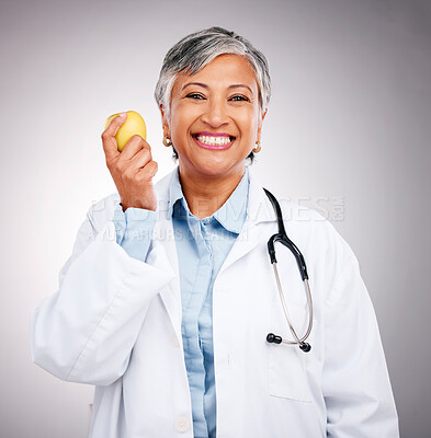 Buy stock photo Woman, doctor and portrait with apple in studio for vitamin c benefits, health and care on grey background. Happy mature dietician, nutritionist and healthy food to lose weight with fruits for detox