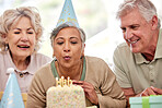 Senior woman, friends and birthday cake for blowing candles, wish and excited with celebration in nursing home. Elderly group, people and together for party, event and hope with culture in retirement