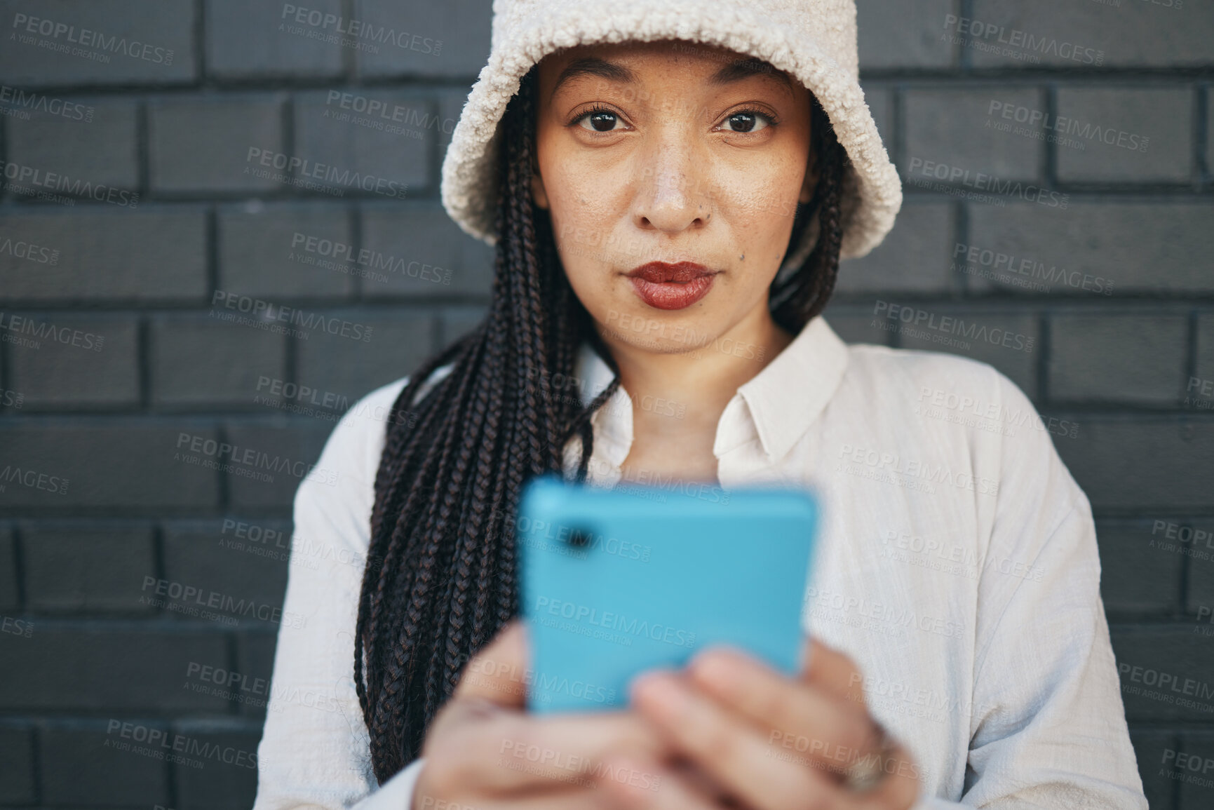 Buy stock photo Portrait of girl with phone, brick wall and urban fashion for social media, typing chat or post online. Streetwear, gen z woman or influencer on smartphone in content creation, communication and tech