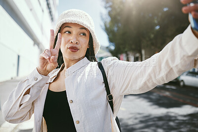 Buy stock photo Woman on city street with selfie, peace sign and travel holiday memory or social media in streetwear. Influencer, streamer or gen z girl with urban fashion, photography and content creation for blog.