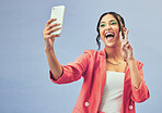 Phone, selfie and happy woman with a peace sign from social media and profile picture for creative job in studio. Influencer and makeup with career fashion with blue background and emoji hand sign