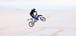Sand, jump or athlete driving motorcycle for action, adventure or fitness with performance or adrenaline. Desert, risk or sports person on motorbike on dunes for training, exercise or race challenge 