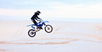 Sand, jump or athlete driving motorcycle for fitness, adventure or action with performance or adrenaline. Desert, risk or sports person on motorbike on dunes for training, exercise or race challenge