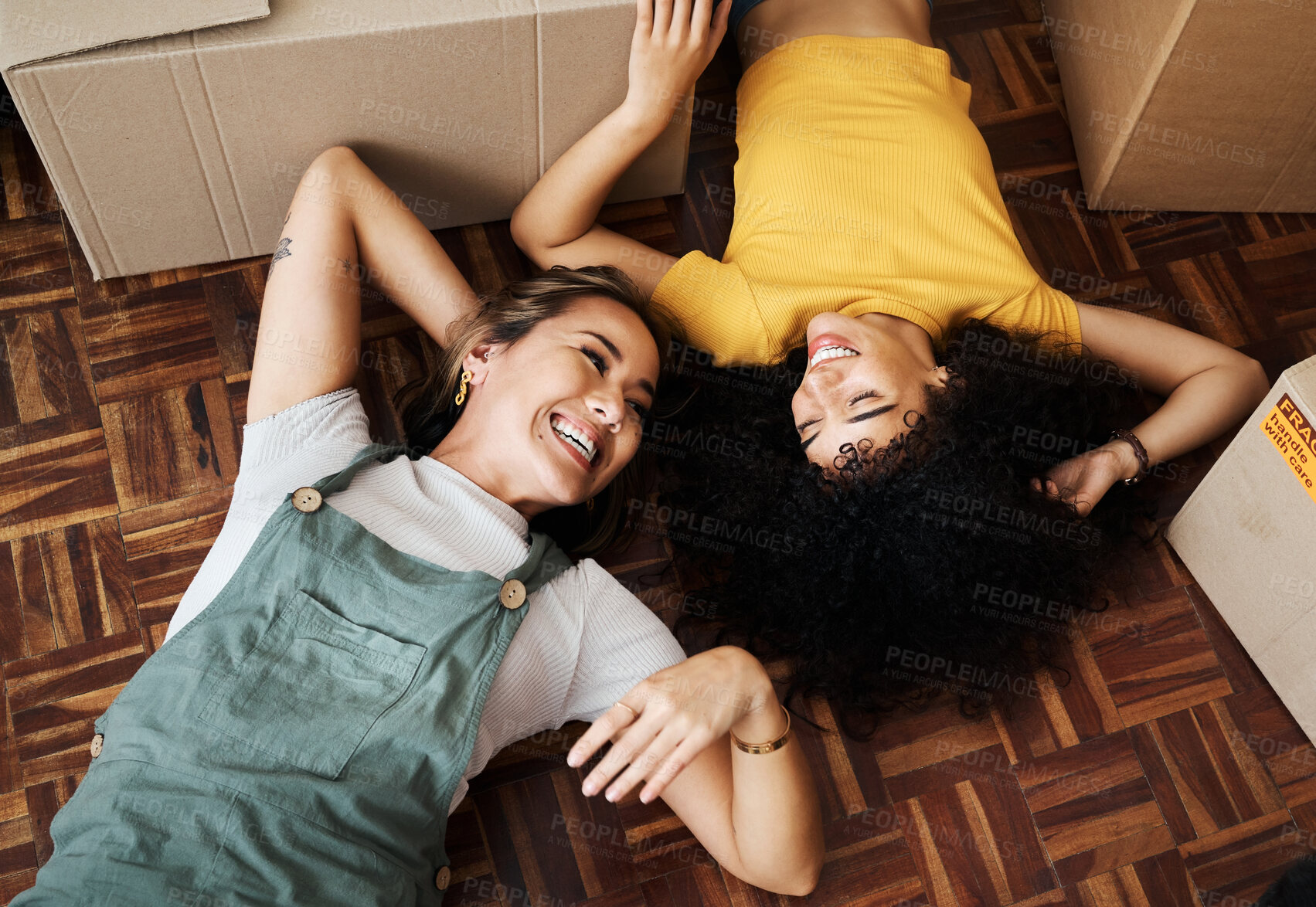 Buy stock photo Top view, lesbian and couple on the floor, boxes and funny with love, bonding and homeowners. Queer people, lgbtq and women on the ground, new apartment and property with achievement and real estate