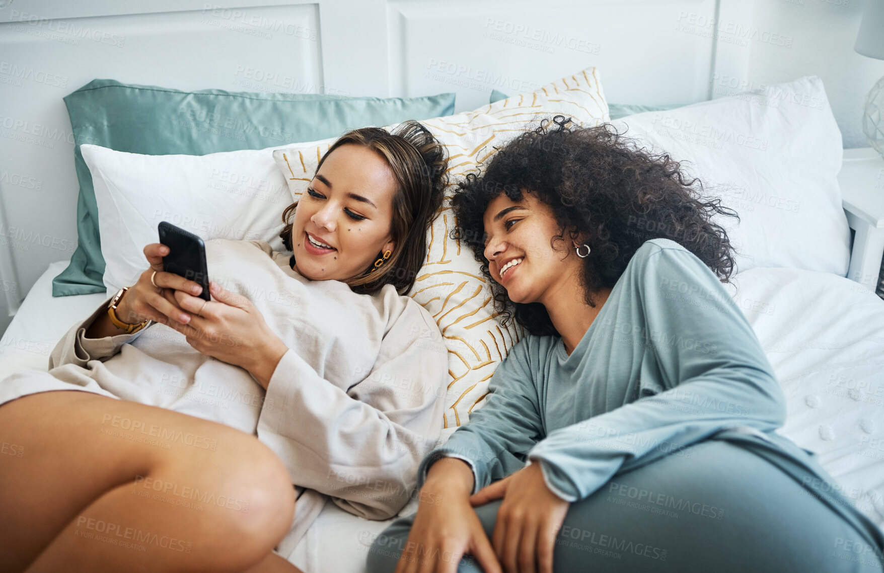 Buy stock photo Phone, social media and a lesbian couple in bed together in the morning for communication or to relax. Love, lgbt and a woman watching a movie or video with her girlfriend in the home bedroom