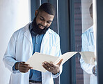 Doctor, man and reading documents, information or paperwork of patient by window in building with smile. Healthcare, professional or person looking at notes or charts on paper with happiness for work