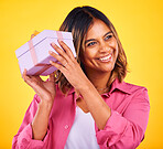 Woman, curious and excited with gift, smile and birthday on a yellow studio background. Person, happy girl and model with a ribbon, present and box with package, surprise and thinking with giveaway