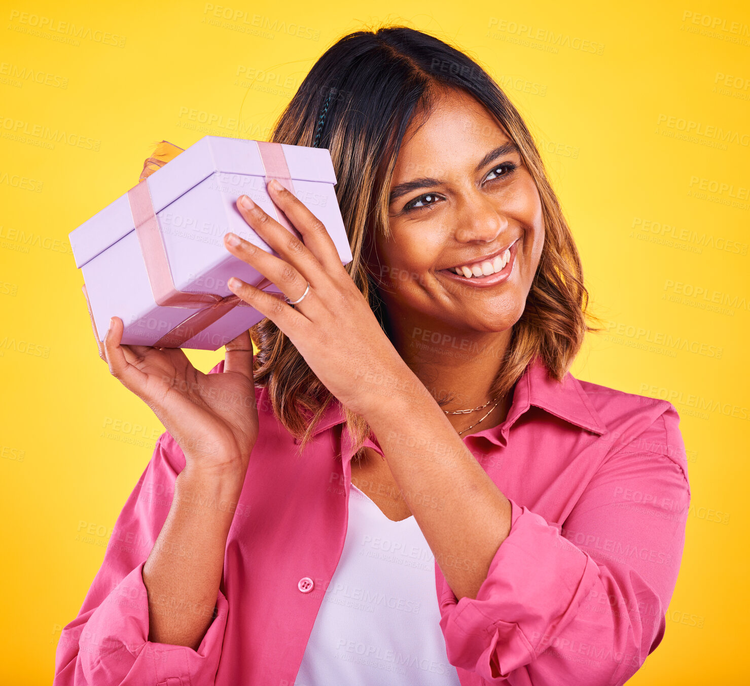 Buy stock photo Woman, curious and excited with gift, smile and birthday on a yellow studio background. Person, happy girl and model with a ribbon, present and box with package, surprise and thinking with giveaway