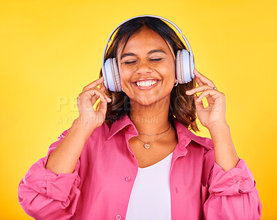 Buy stock photo Headphones, smile and young woman in a studio listening to music, playlist or radio for entertainment. Happy, technology and female model from Mexico streaming a song or album by yellow background.