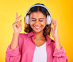 Headphones, happy and young woman in a studio listening to music, playlist or radio for entertainment. Smile, technology and female model from Mexico streaming a song or album by yellow background.