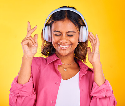 Buy stock photo Headphones, happy and young woman in a studio listening to music, playlist or radio for entertainment. Smile, technology and female model from Mexico streaming a song or album by yellow background.