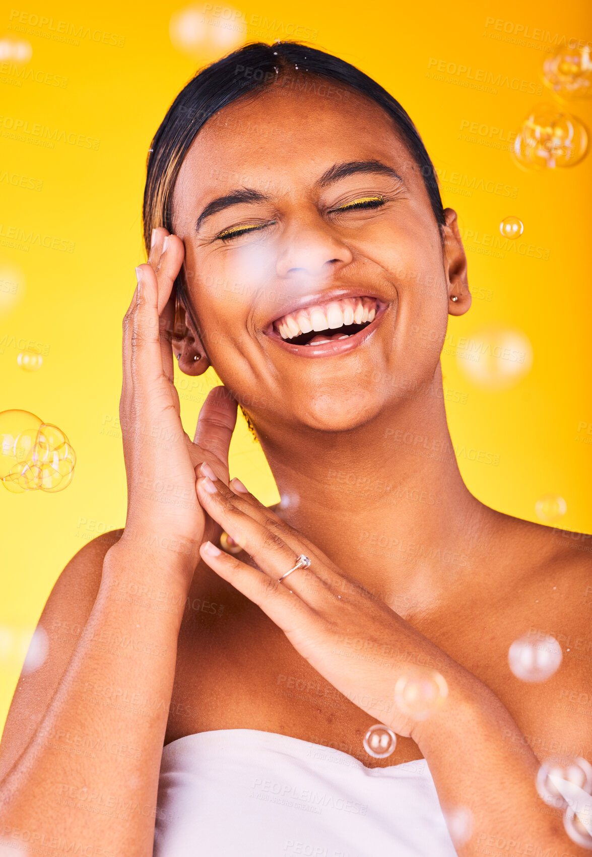 Buy stock photo Face, beauty and bubbles with a woman laughing on a yellow background in studio for freedom, energy or wellness. Skincare, smile and funny with a happy young natural model cleaning for hygiene