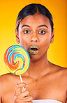 Shock, lollipop and portrait of woman in studio with makeup, cosmetic and face routine. Surprise, beauty and young Indian female model with colorful candy and facial cosmetology by yellow background.
