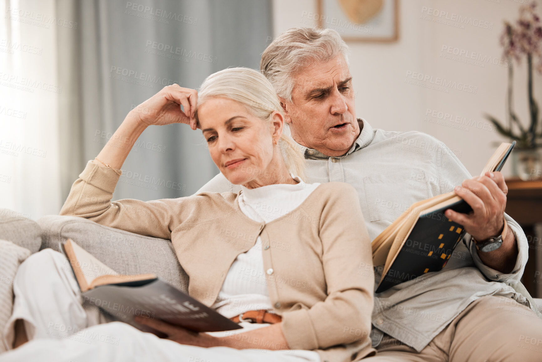 Buy stock photo Old couple on sofa, reading book and relax together at home, retirement and wellness with love and comfort. Trust, care and support in marriage, share hobby with partner for knowledge and story