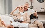 Senior, couple and reading book on a living room sofa with love, smile and retirement in a home. Elderly people, story and lounge on a couch with study for knowledge in a house happy and relax 