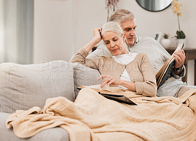 Buy stock photo Old couple on couch, reading book and relax together at home, retirement and wellness with love and comfort. Trust, care and support in marriage, share hobby with partner for knowledge and story