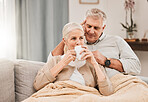 Old couple, hug and relax on couch with coffee, love and support, bonding while at home with trust and comfort. People have tea together, marriage or partner with retirement, calm and peace of mind